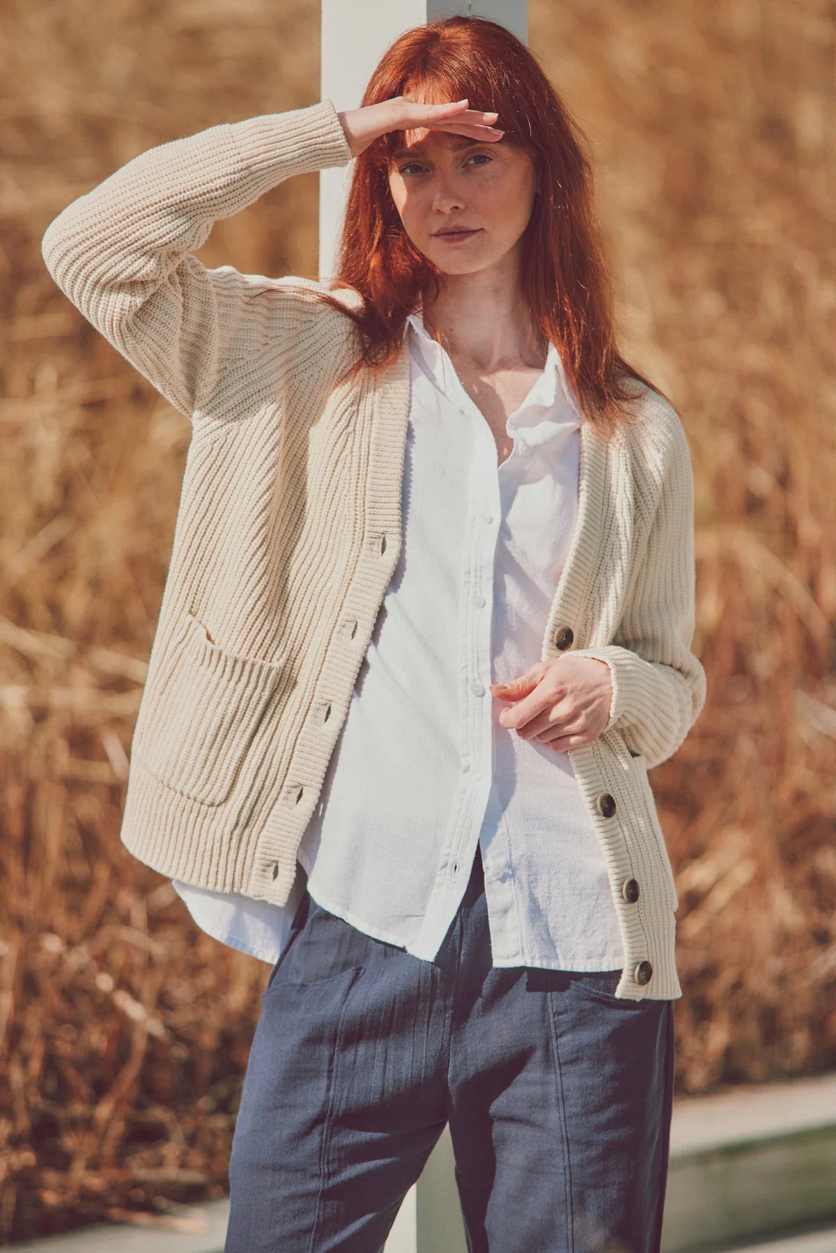 a model in a beige cardigan and white shirt