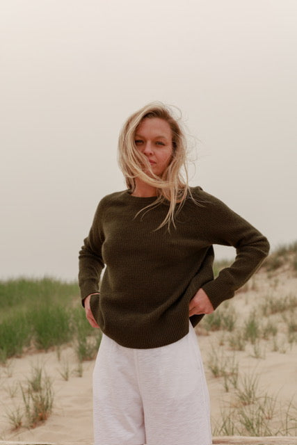 a model in a chocolate brown sweater and white pants