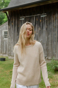 a blonde model in a beige sweater