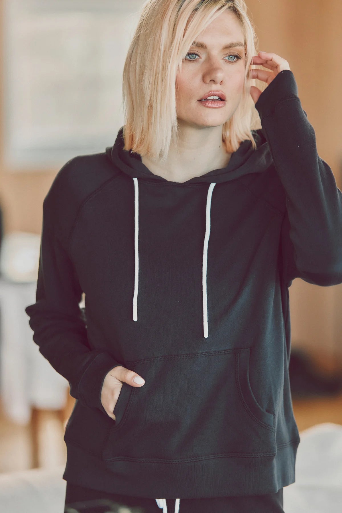 a blonde model in a black hoodie