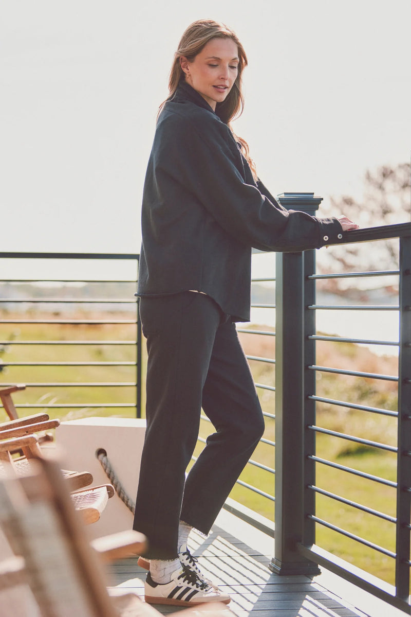 Side view of a woman in a black Dartmouth Jacket, styled with black pants