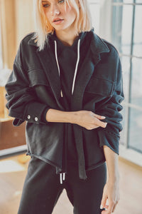 Close-up of woman adjusting the sleeve of a black Dartmouth Jacket over a hoodie