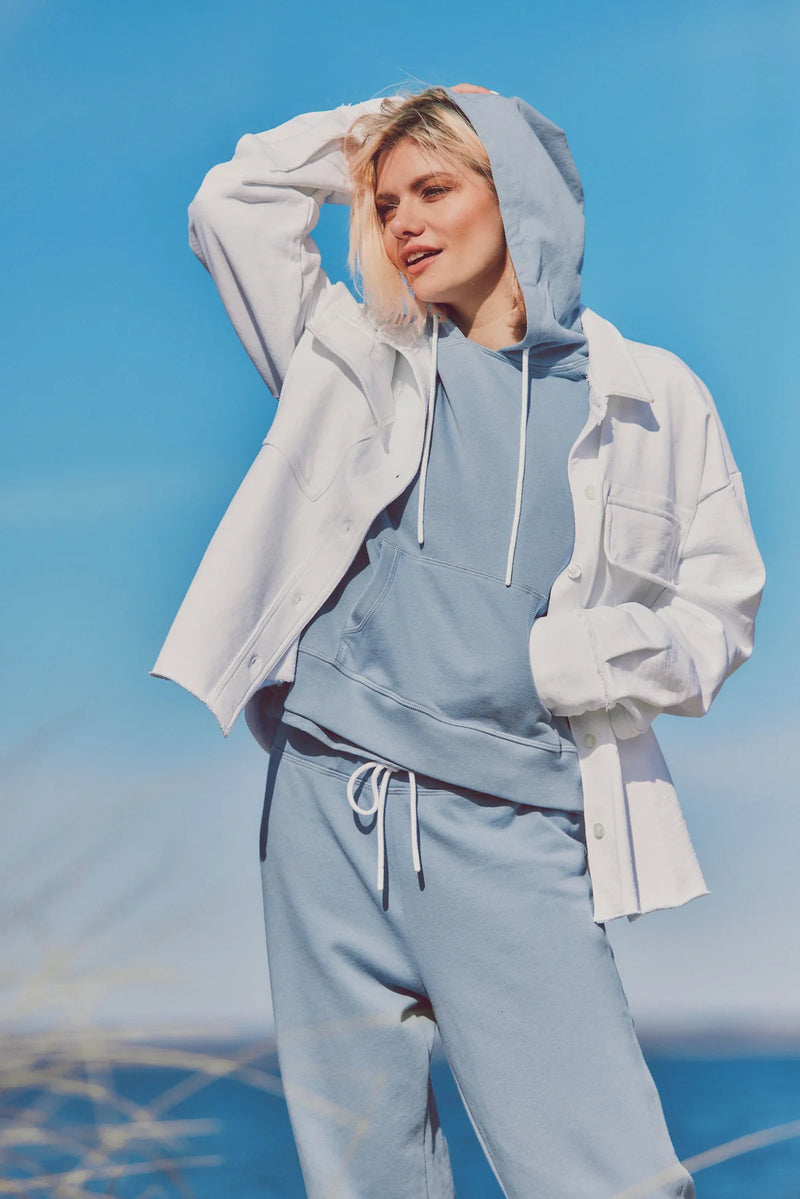 Woman wearing a white Dartmouth Jacket layered over a blue hoodie and joggers