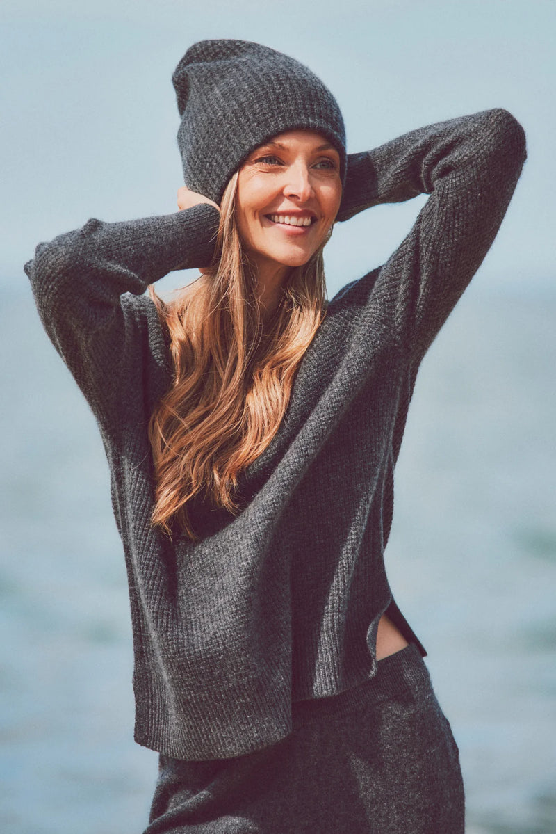 a model adjusting her beanie and a gray knit sweater