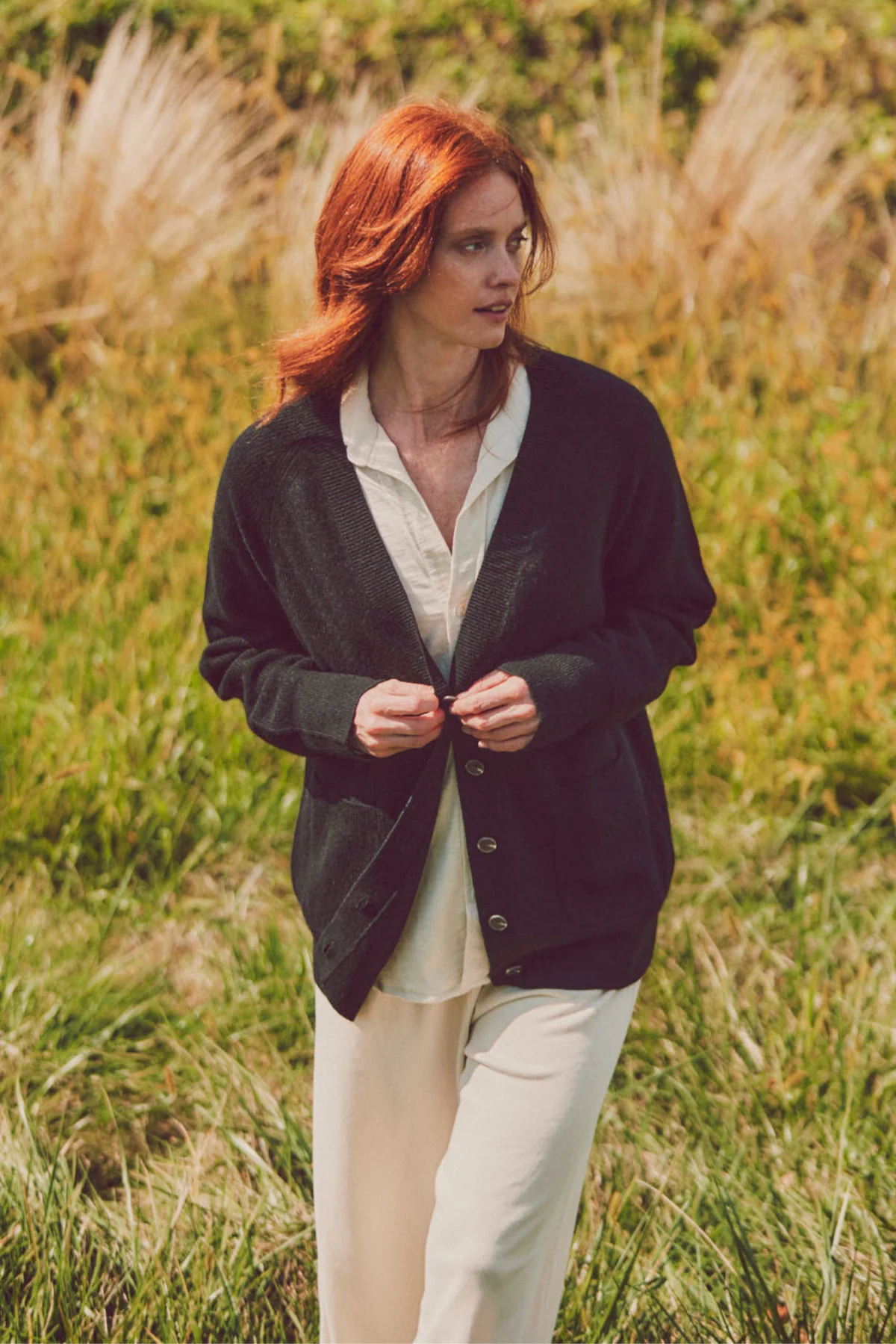 a model buttoning up a black cardigan