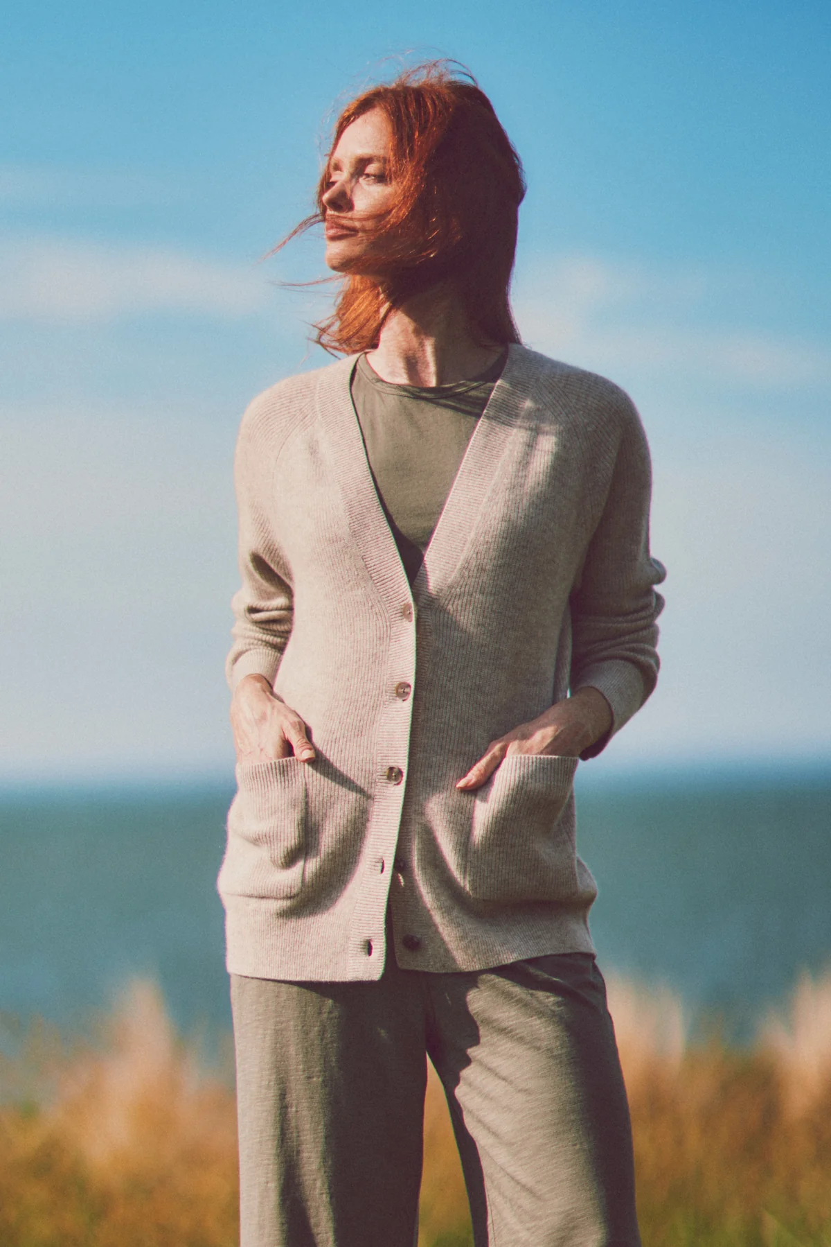 a model with hands in pockets of a gray cardigan