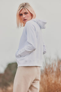 a model with hands in pockets of a white hoodie