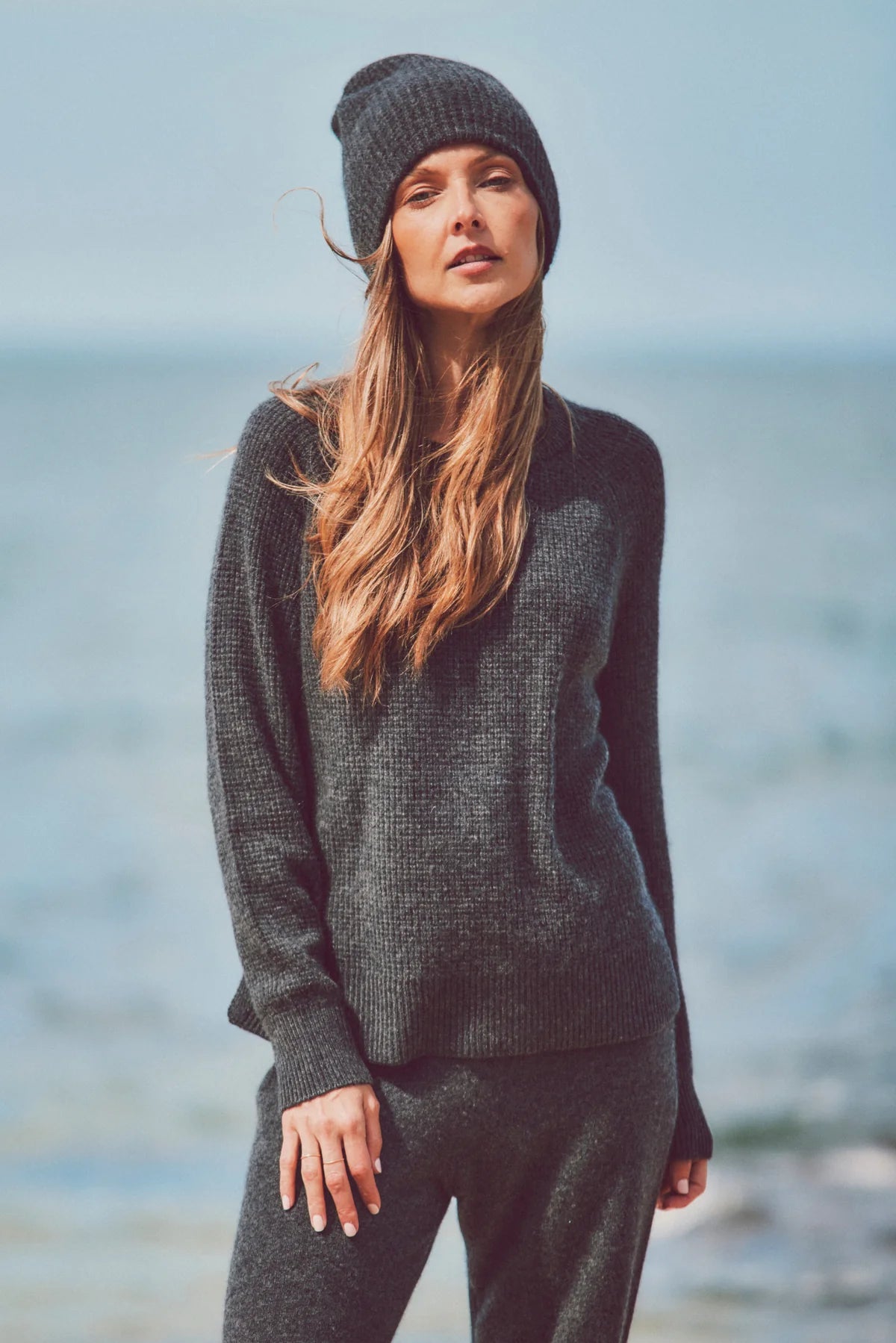 a model in a beanie, knit sweater, and pants