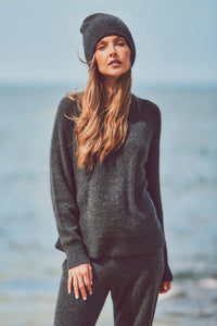 a model in a beanie, knit sweater, and pants