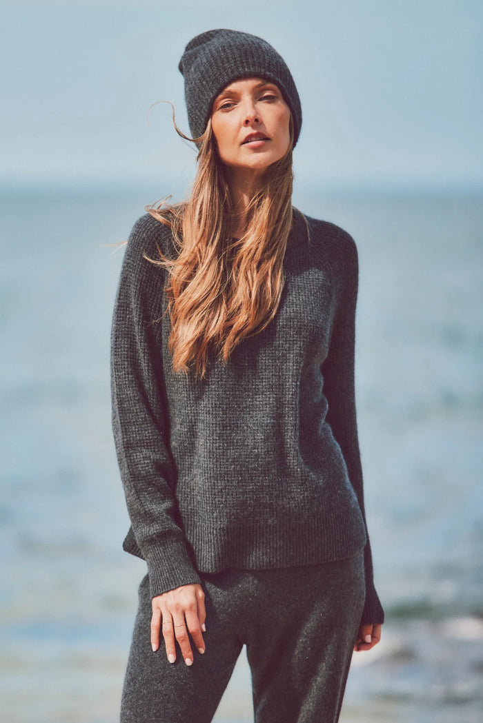 a model in a beanie, knit sweater, and pants