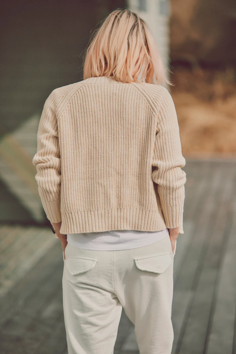 a model in a beige cardigan facing away from the camera