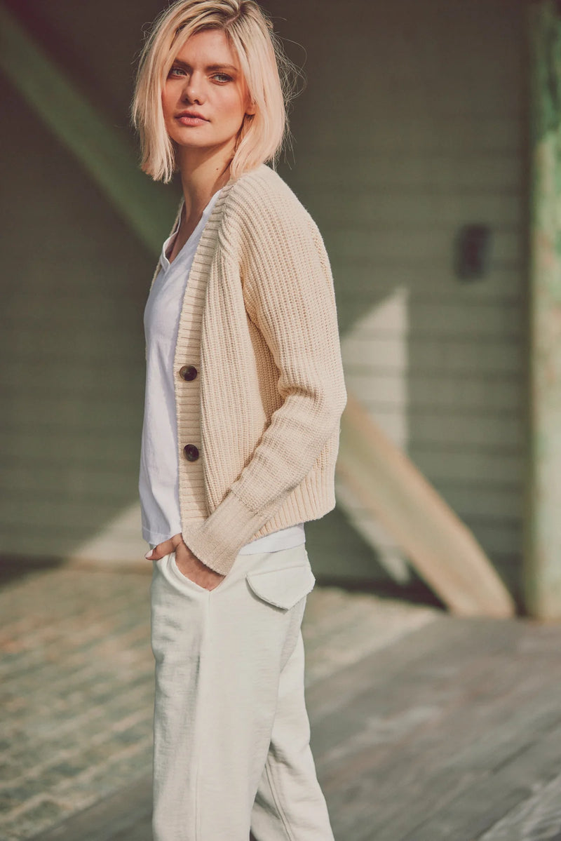 a model in a beige cardigan and white lounge pants