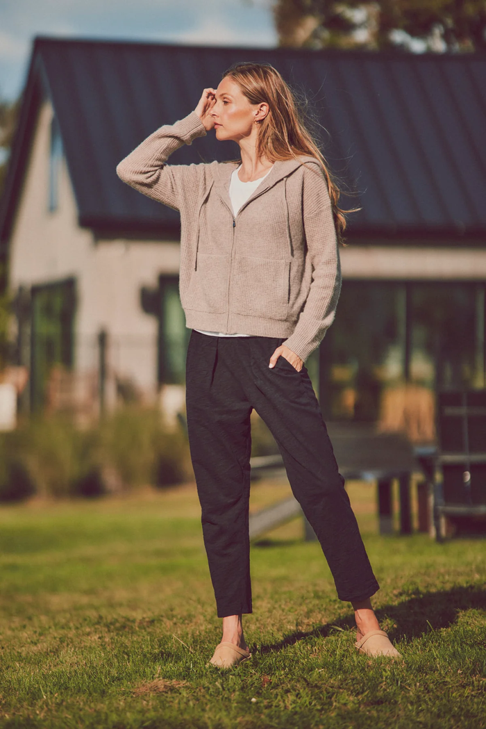 a model in a beige hoodie black pants