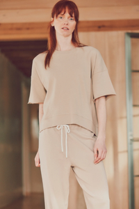 a model with red hair in beige joggers and a t-shirt