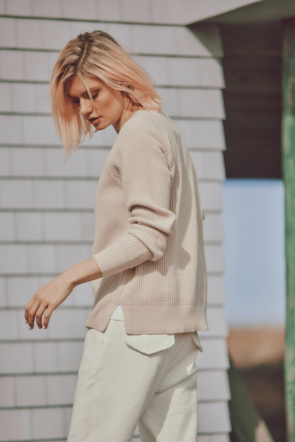 a model in a beige sweater and cream pants