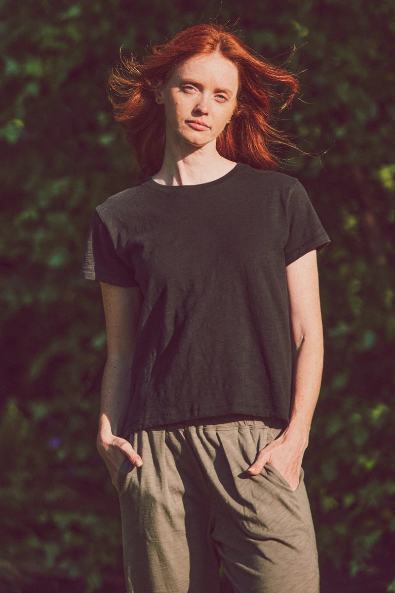 a model in a black tee and olive pants