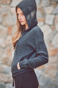 a model in a charcoal hoodie with the hood up