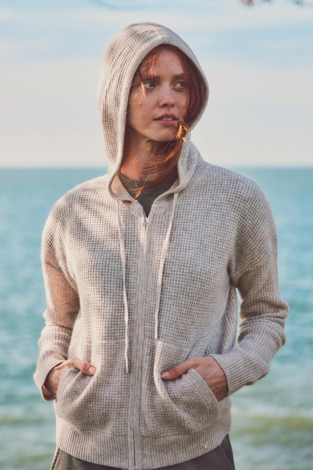 a model in a cream hoodie with hands in pockets