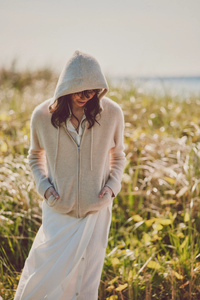 a model by a field in a beige hoodie