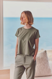 a model near a window in a green t-shirt and pants