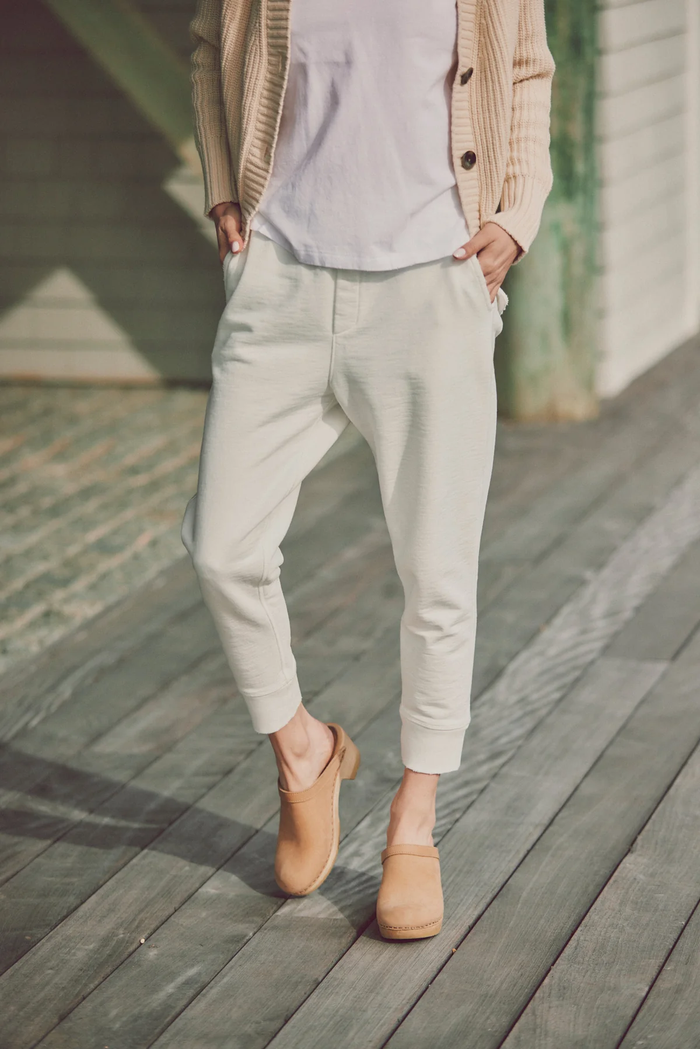 a model in light-colored joggers and a t-shirt with a beige cardigan