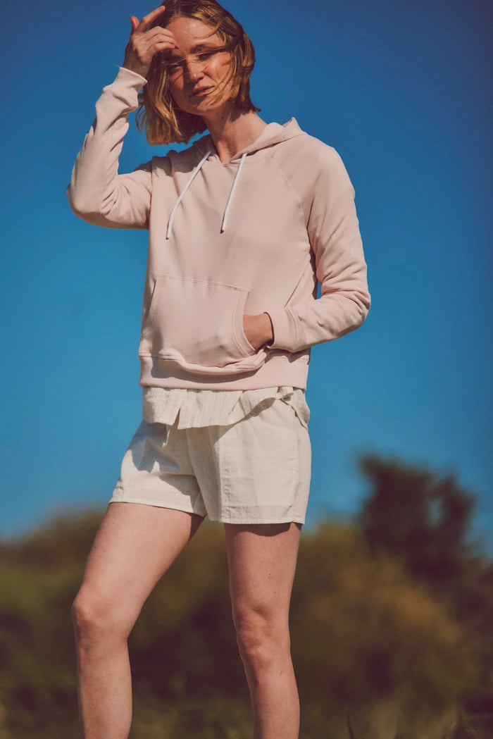 a model in a light pink hoodie and shorts