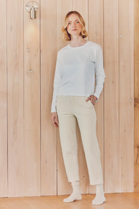 a model in a white long-sleeve and beige pants