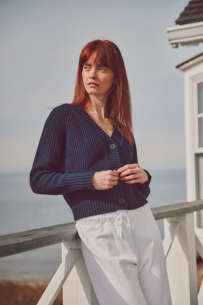 a model in a navy cardigan and white pants