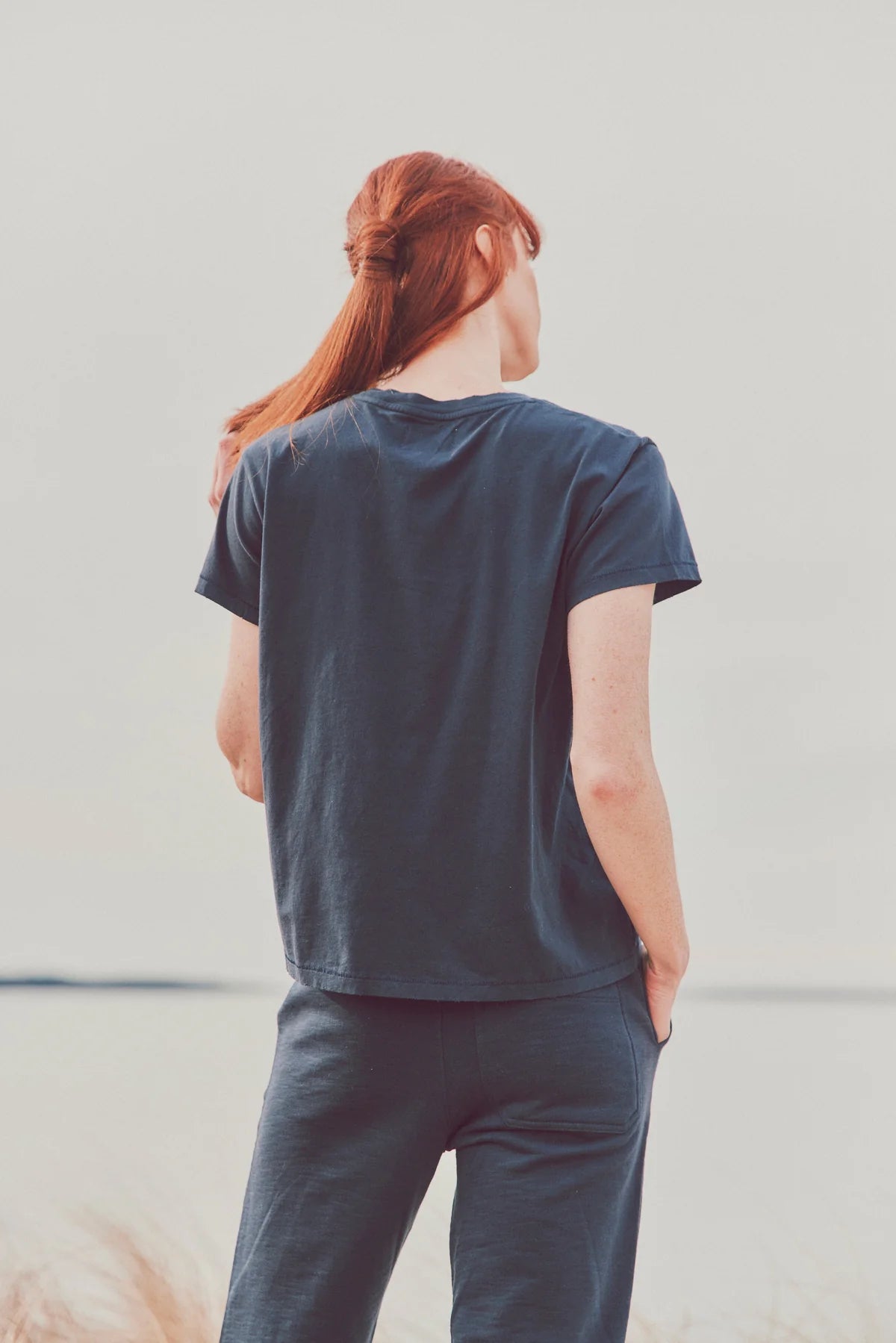 a model facing away from the camera in a navy tee and pants