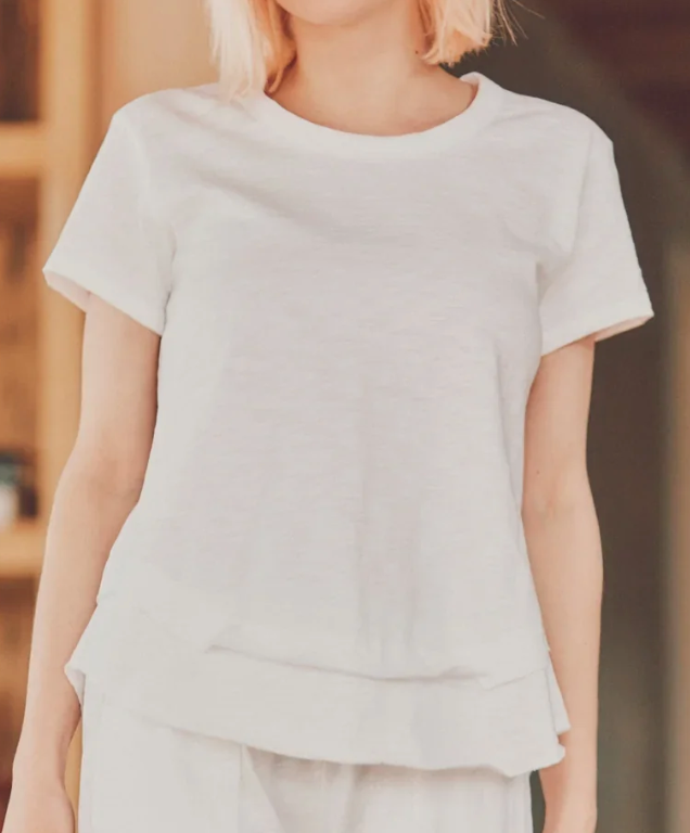 a model in a white ruffle bottom tee