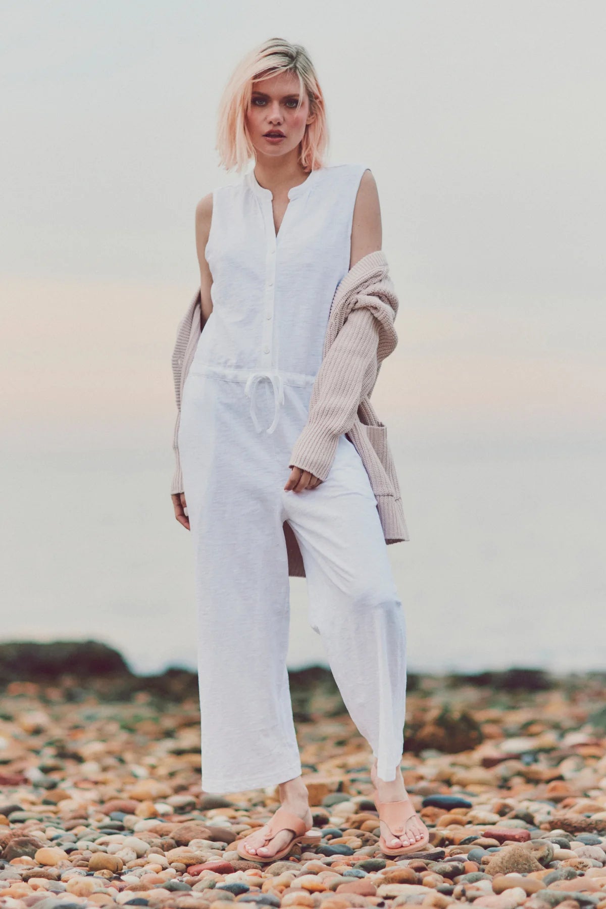 a model in a white jumpsuit and cardigan