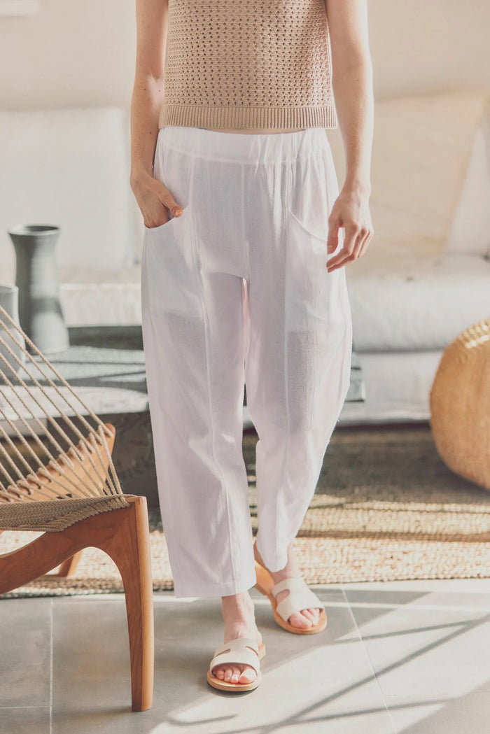 a model in white cotton pants and white sandals