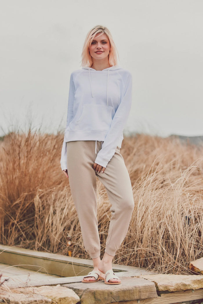 a model in a white sweater and beige pants