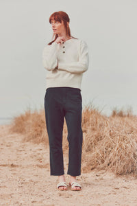 a model in a white sweater and navy pants