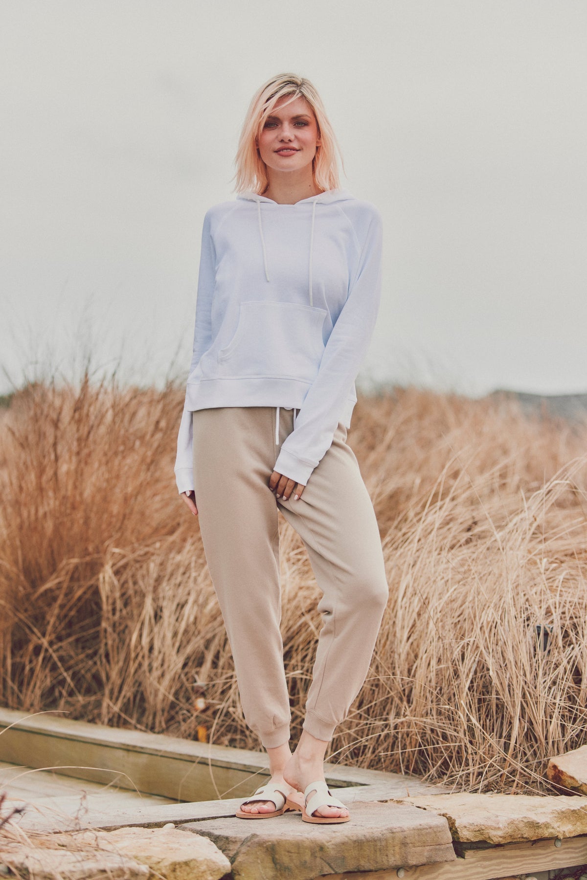 a model in a white sweatshirt and beige joggers