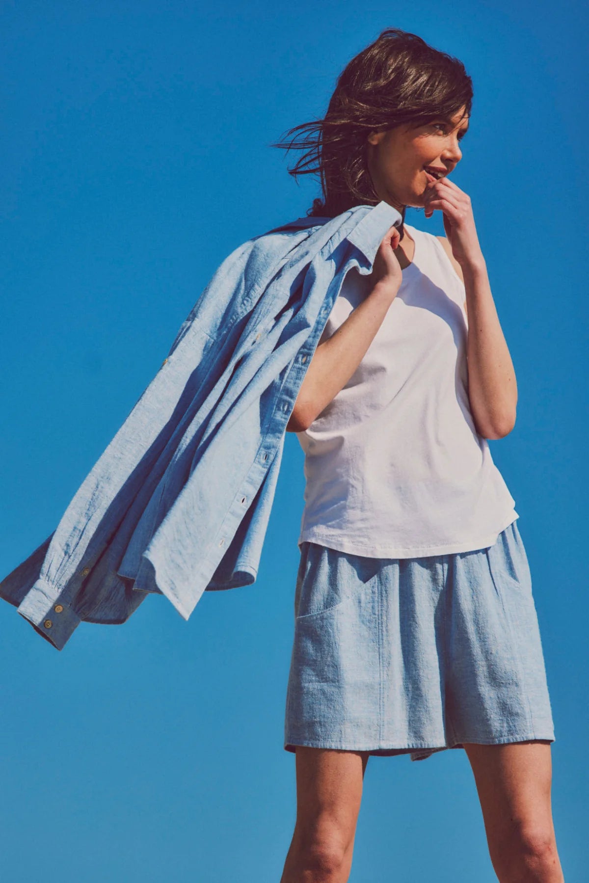 a model in a white t-shirt with blue shorts and a button-up