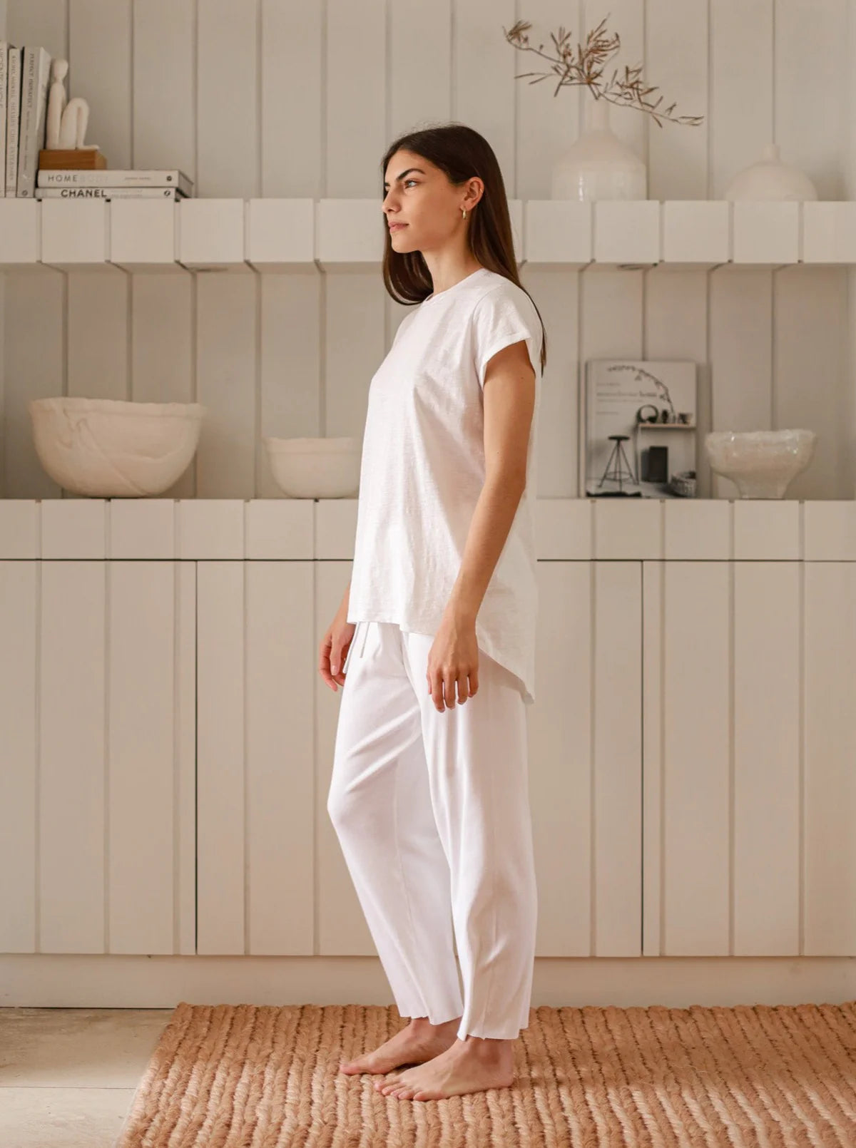a model wearing a white hi-lo t-shirt and white flowy pants.