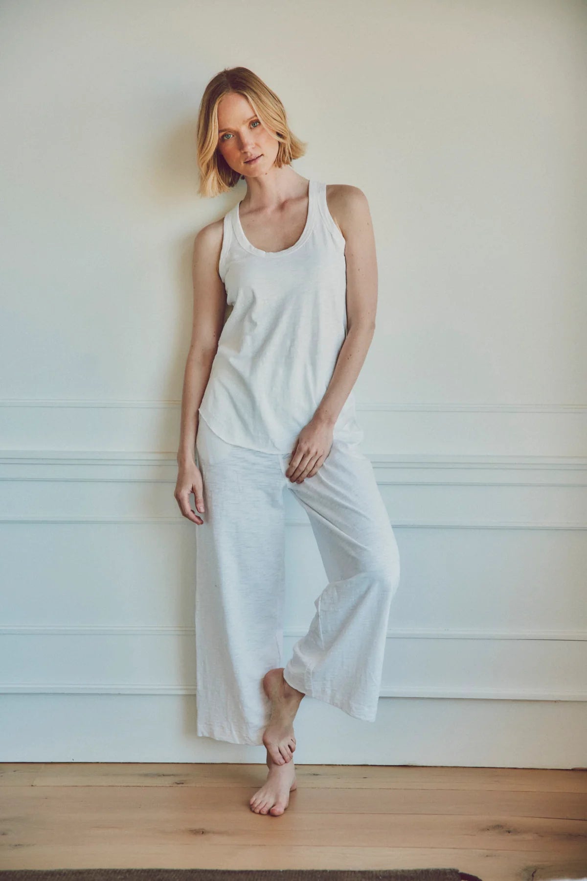 a model wearing a white tank top with white poppy wide-leg pants