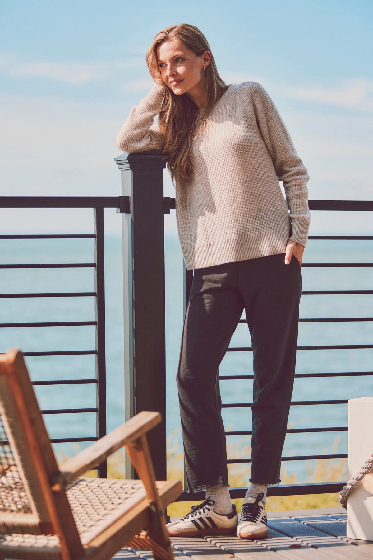 a model leaning on a post in a beige sweater