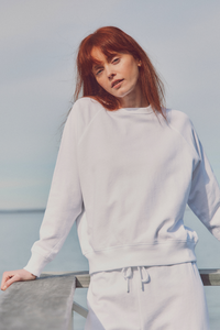 a model leaning on a railing in a white sweat set