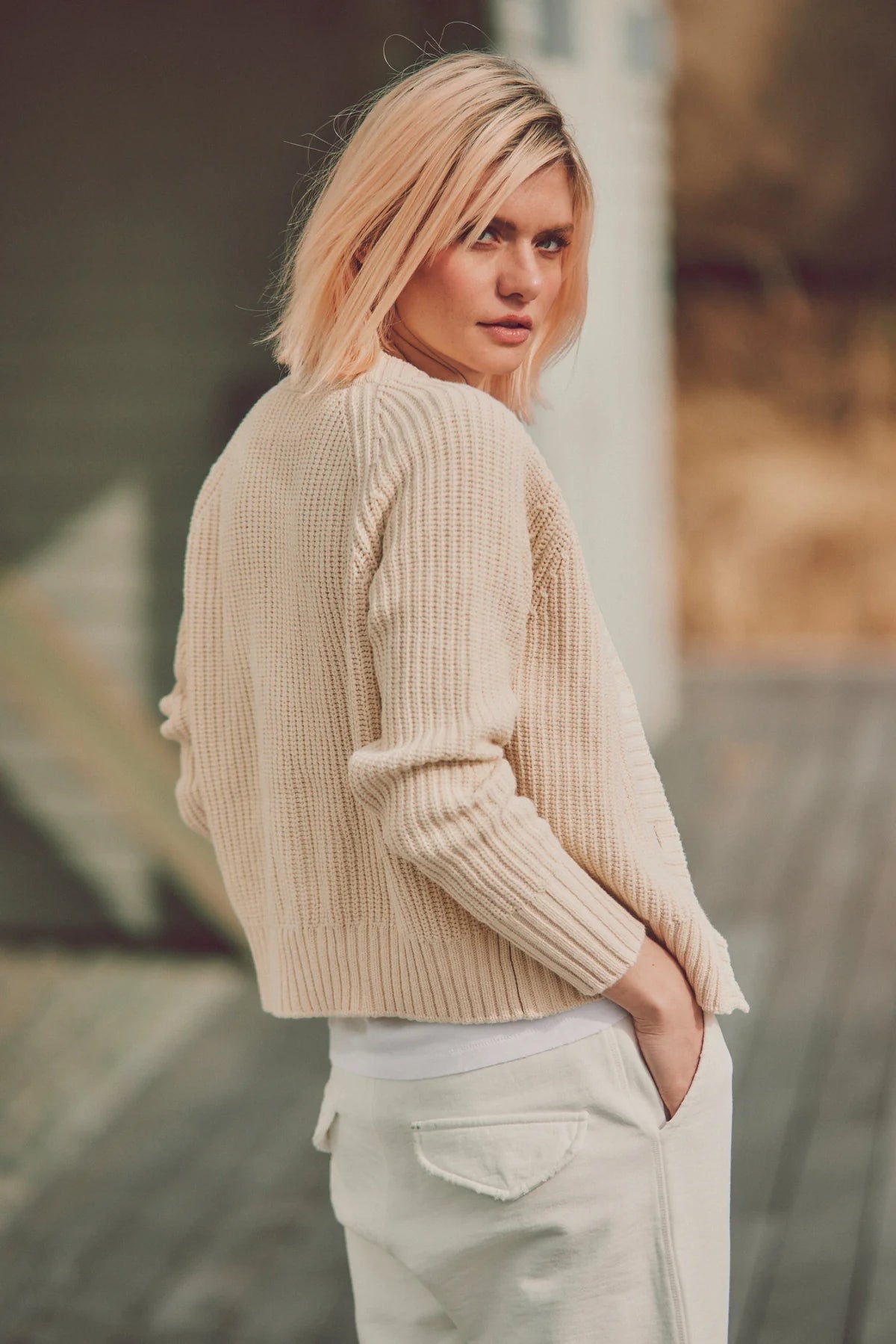 a model looking over her shoulder in a beige cardigan