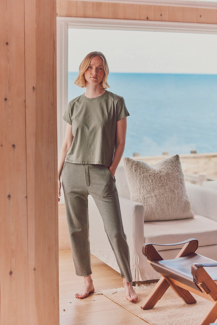 a model near a window in a green tee and matching pants