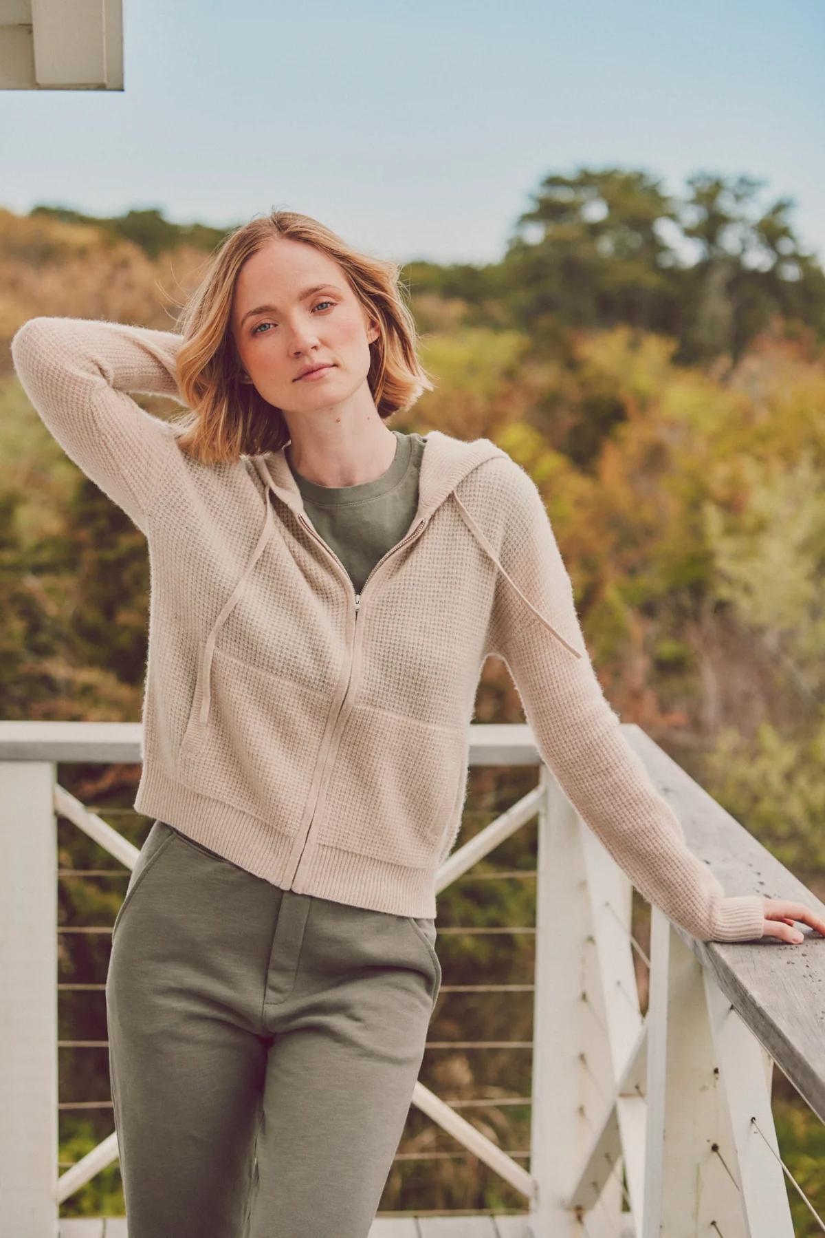 a model on a balcony in a beige hoodie