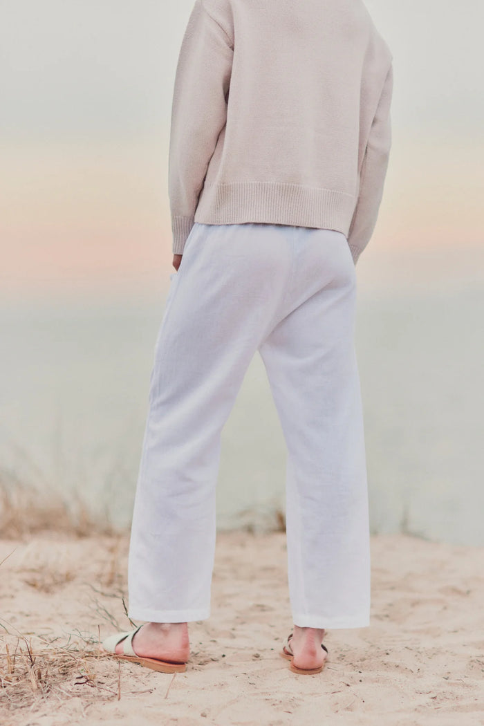 a model on the beach showing the back of white cotton pants