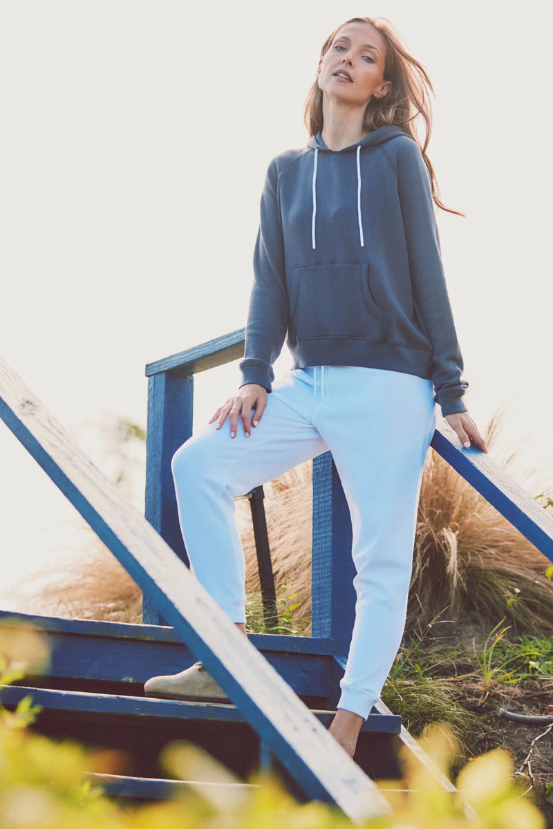 a model on stairs in a blue hoodie and white pants