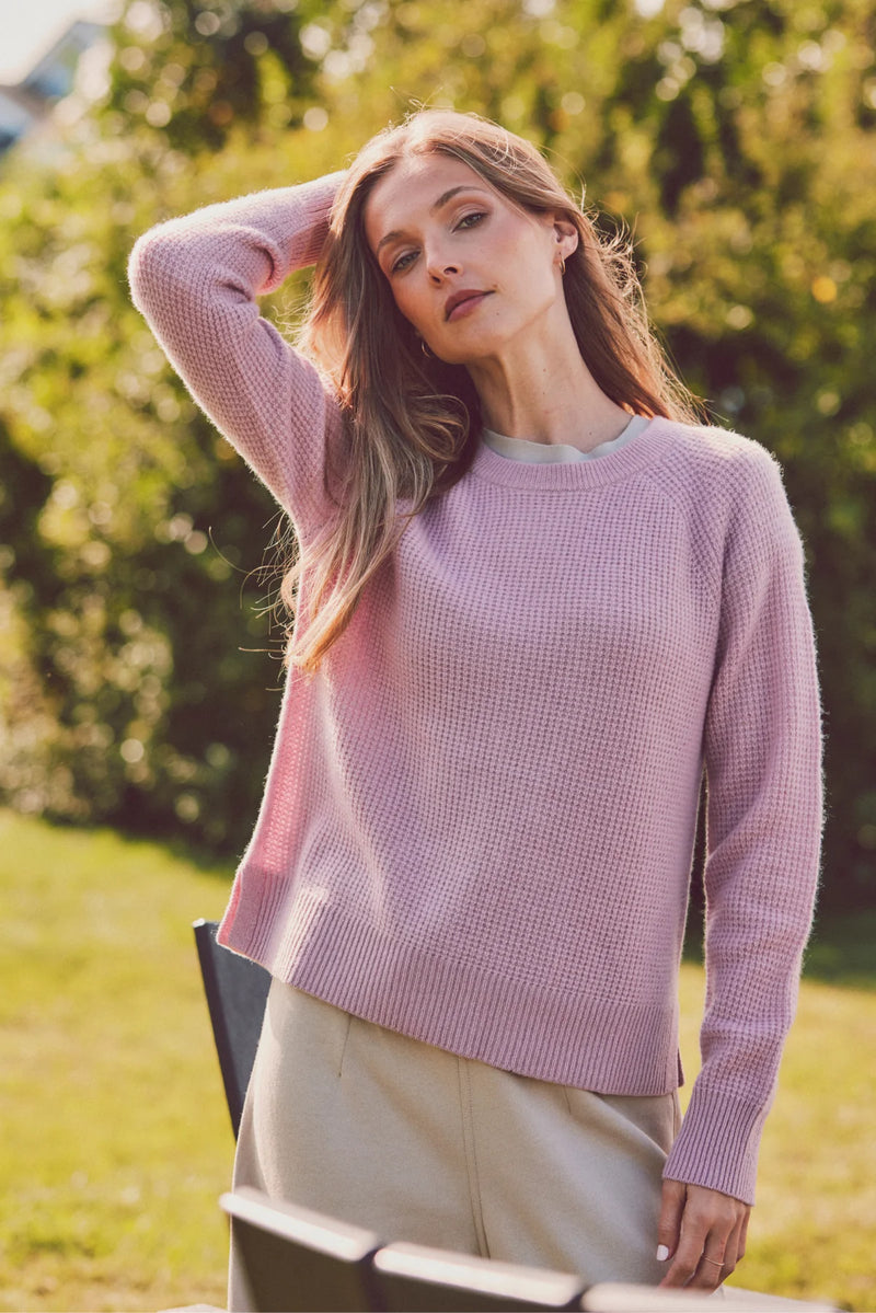 a model outside in a pink knit sweater