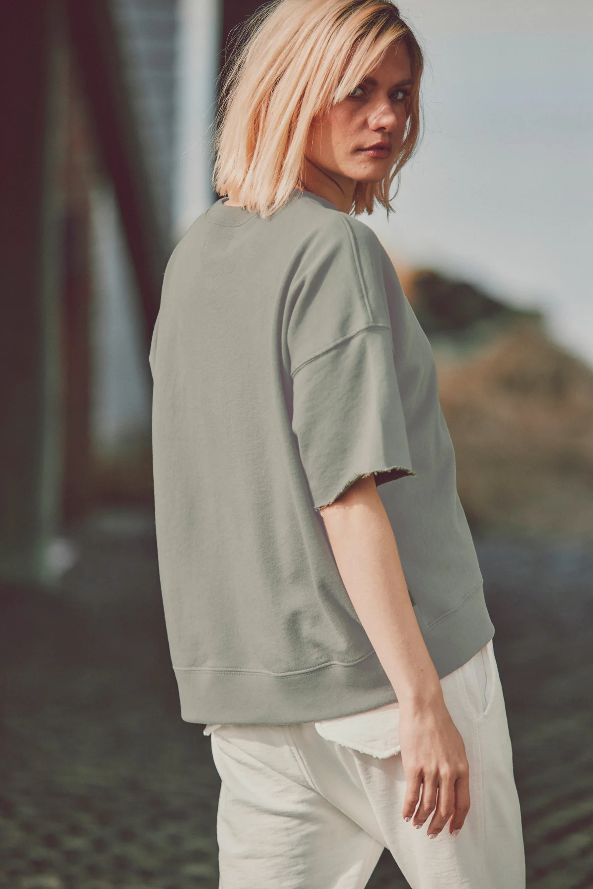 a model outside in white joggers and a green t-shirt