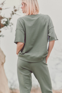 model outside showing the back of green joggers and a t-shirt