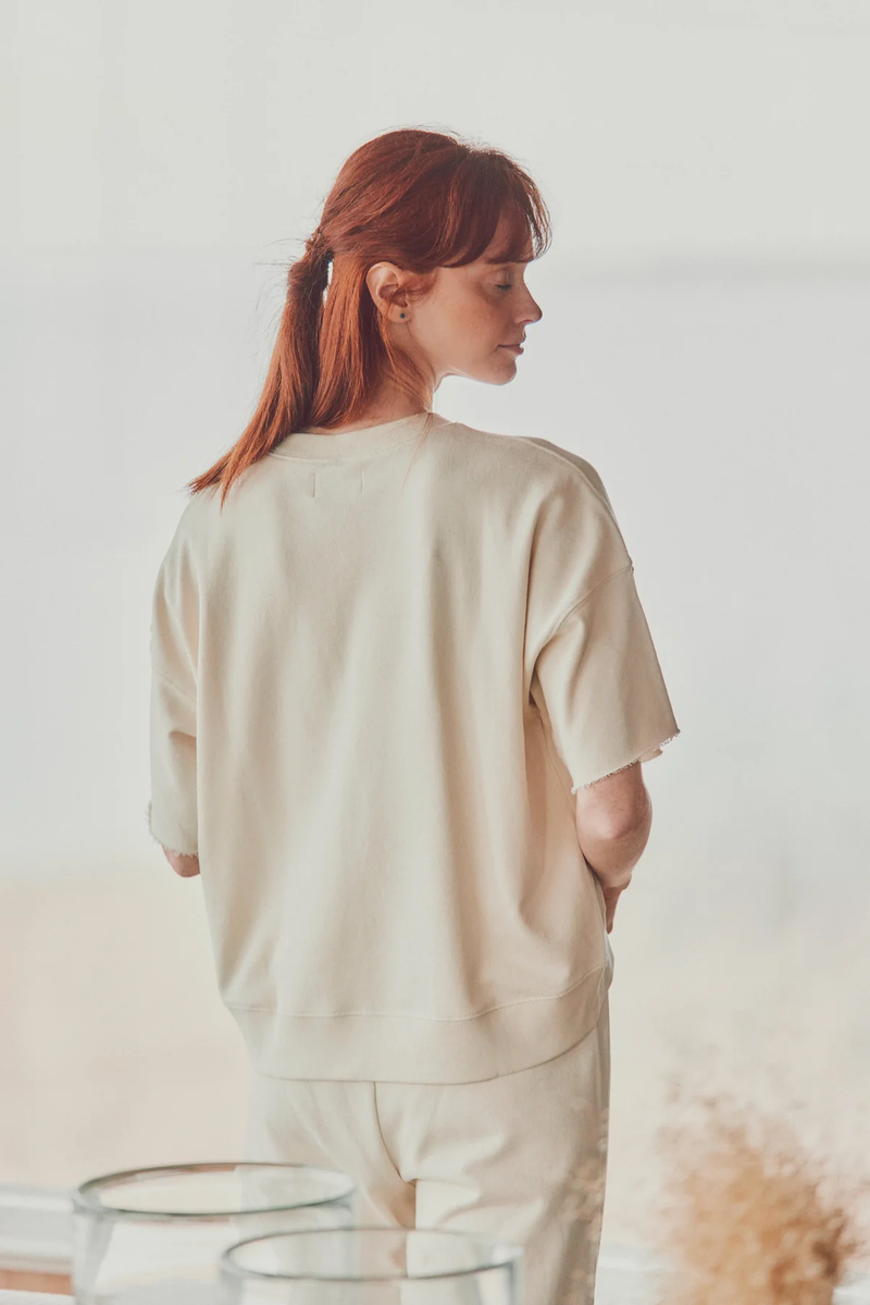 a model showing the back of beige joggers and a t-shirt