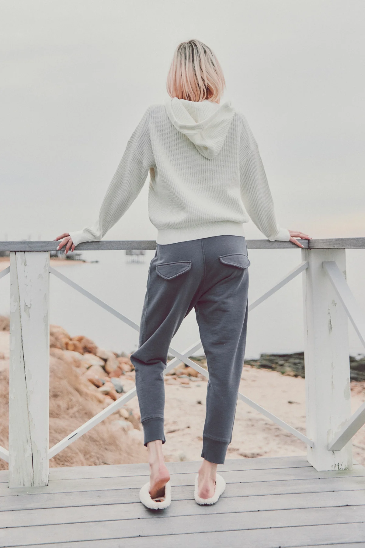 a model showing the back of a white sweater and navy joggers